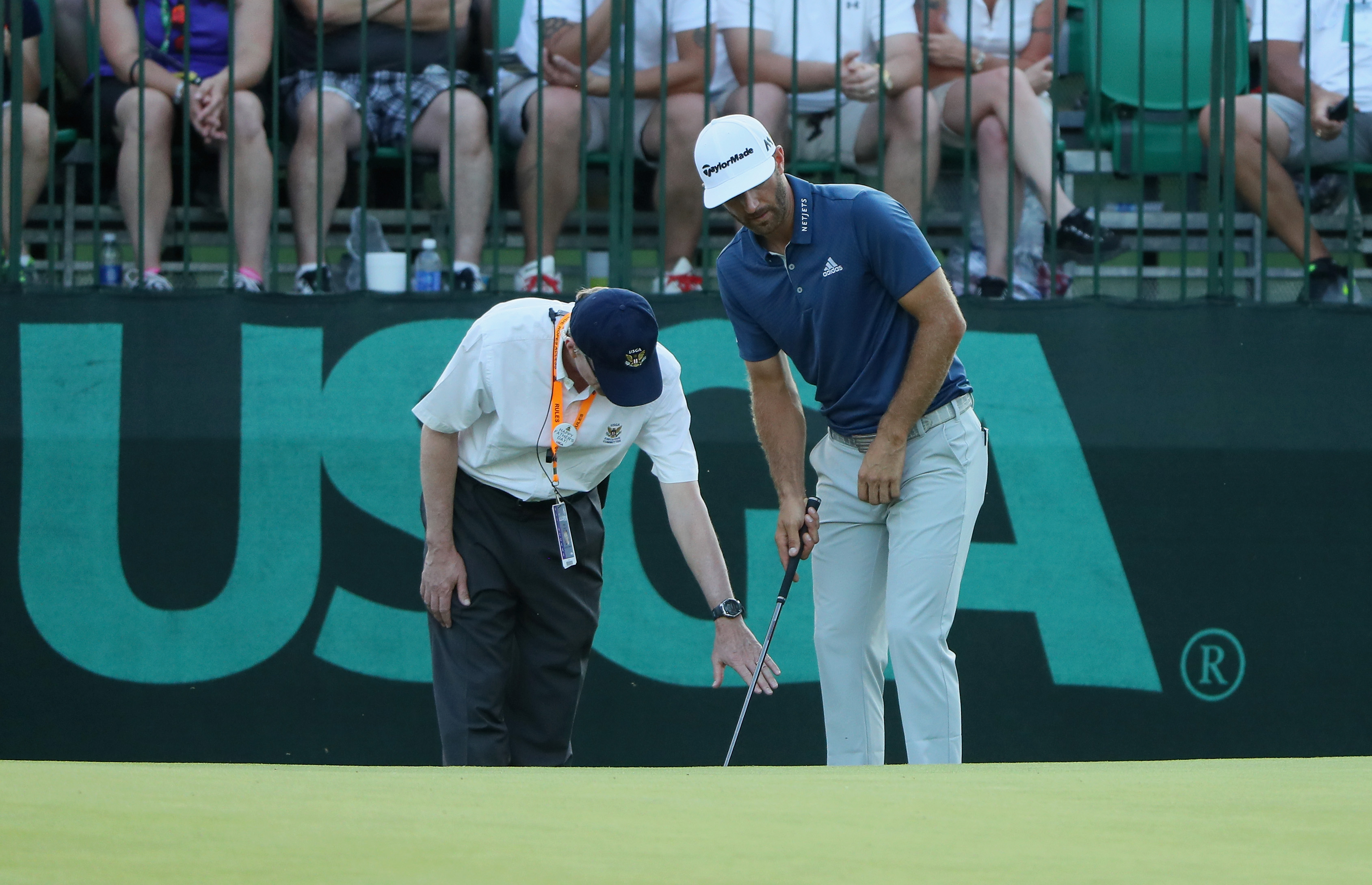 Dustin Johnson en een referee in het US Open nadat de bal op de green verrold was.
